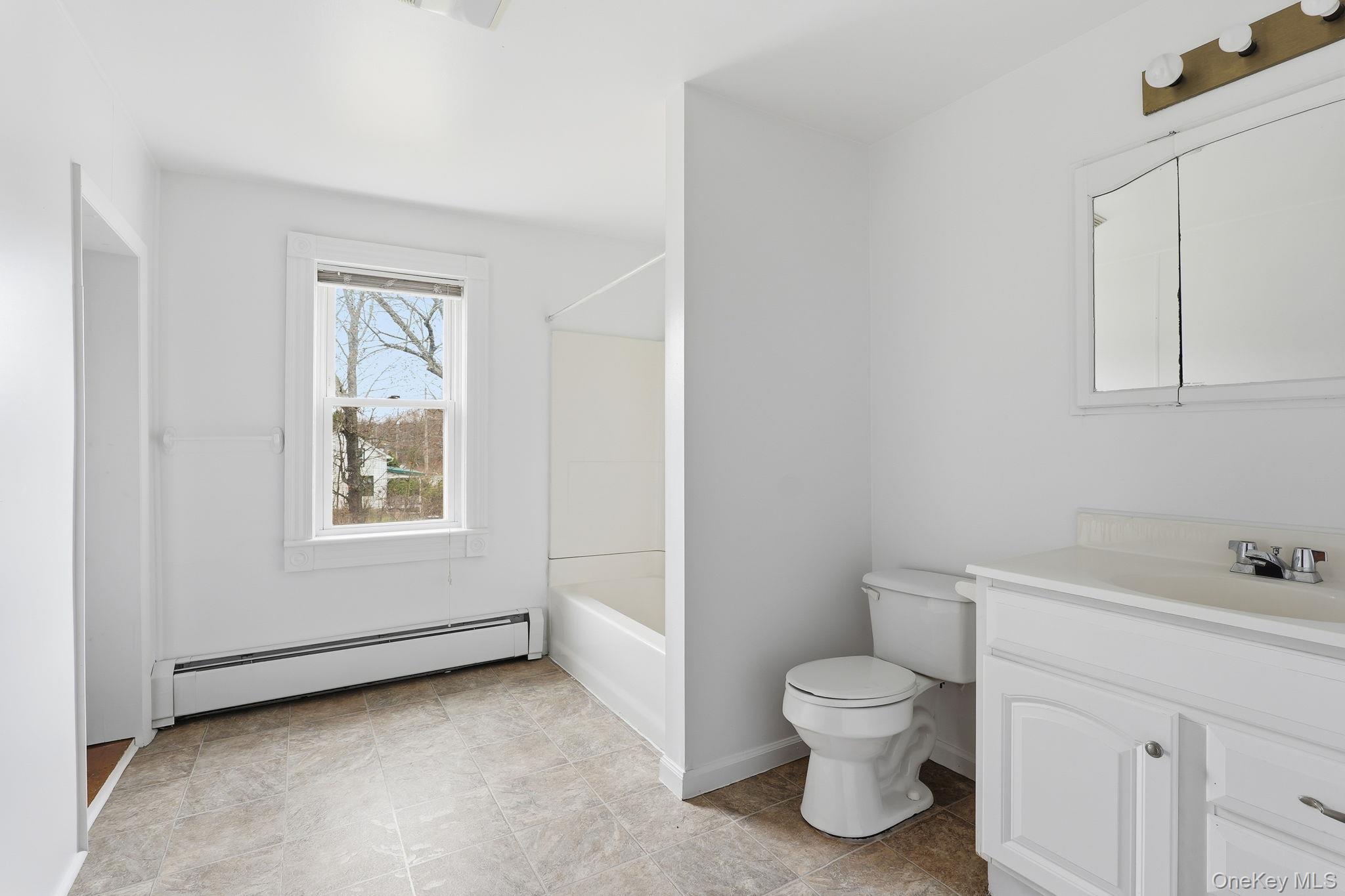 708 Burlingham Road Bloomingburg, NY 12721 - Photo 19 of 25 Bathroom featuring a baseboard heating unit, vanity, and bathtub / shower combination