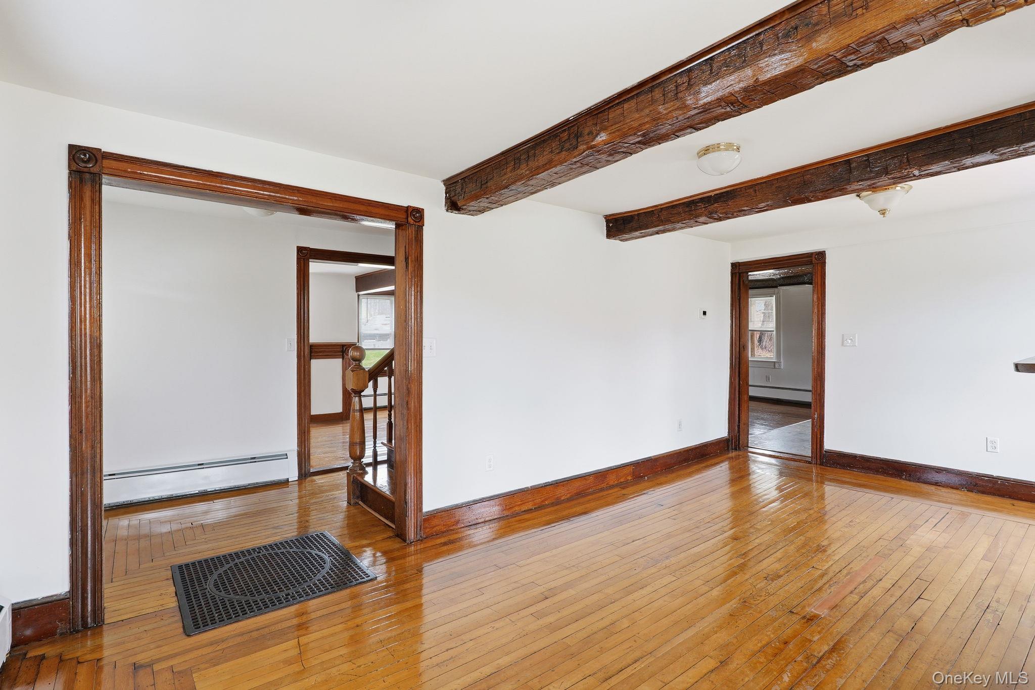 708 Burlingham Road Bloomingburg, NY 12721 - Photo 4 of 25 Empty room featuring baseboard heating, hardwood / wood-style floors, and beamed ceiling