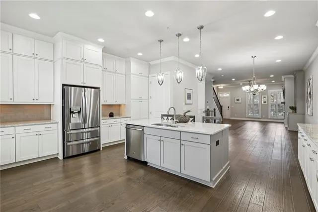 a large white kitchen with lots of counter space wooden floor and stainless steel appliances