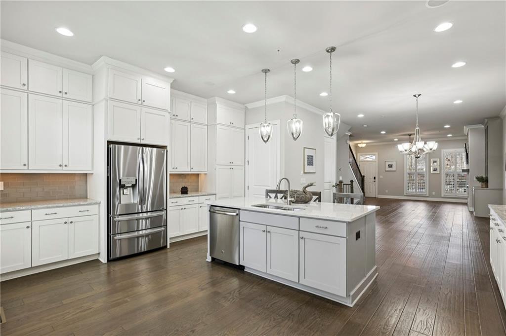 355 Cricket Lane Alpharetta, GA 30009 - Photo 14 of 39 a kitchen with stainless steel appliances kitchen island a refrigerator oven a sink a stove and white cabinets with wooden floor