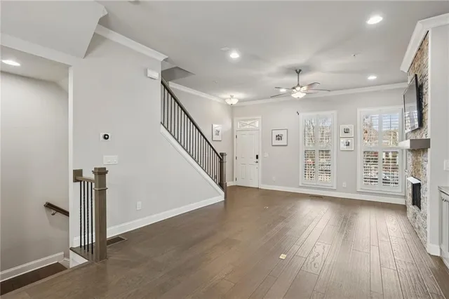 a view of an empty room with wooden floor and a kitchen