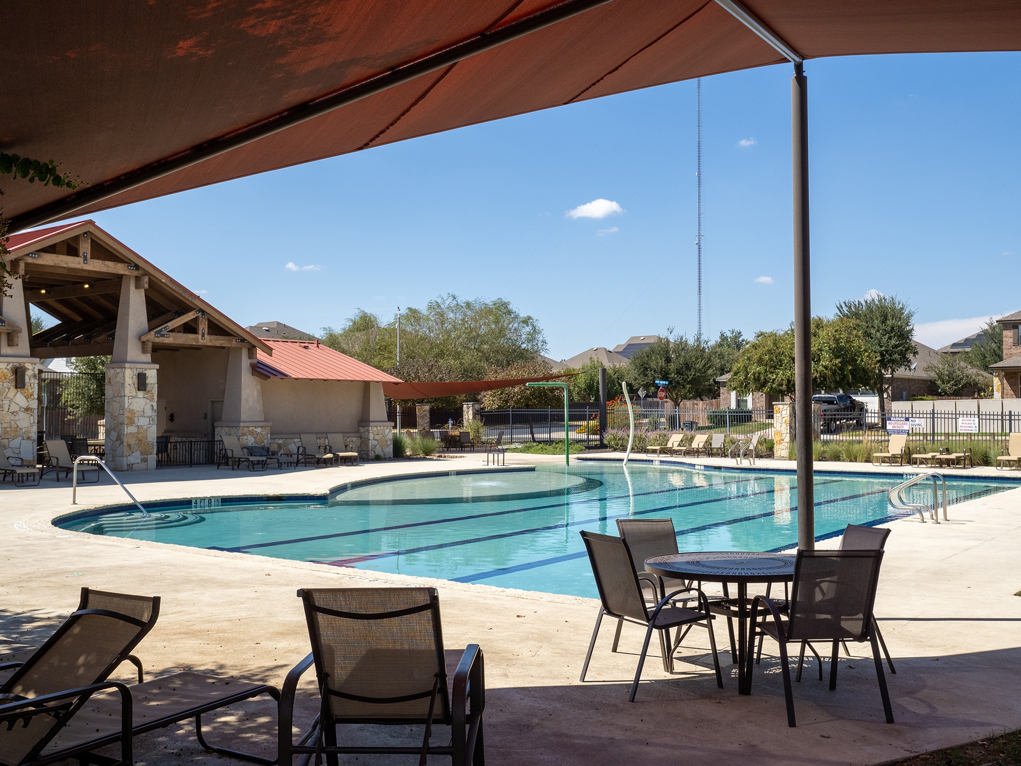 104 Rocroi Drive Georgetown, TX 78626 - Photo 36 of 40 Shaded concrete patios border a large community swimming pool under open skies.