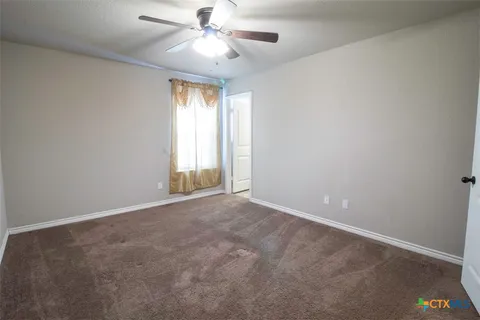 an empty room with windows and fan chandelier fan