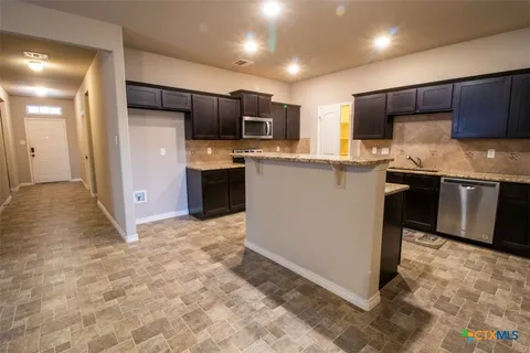 a kitchen with stainless steel appliances granite countertop a refrigerator and a stove top oven