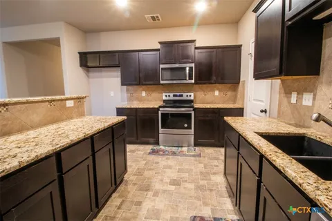 a kitchen with stainless steel appliances granite countertop a sink stove and refrigerator