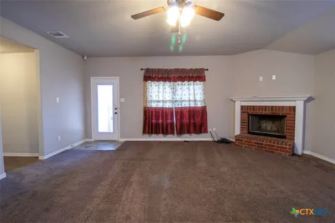 an empty room with windows fireplace and fan