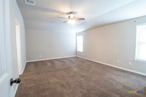 an empty room with windows and chandelier fan