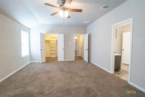 an empty room with chandelier fan and windows
