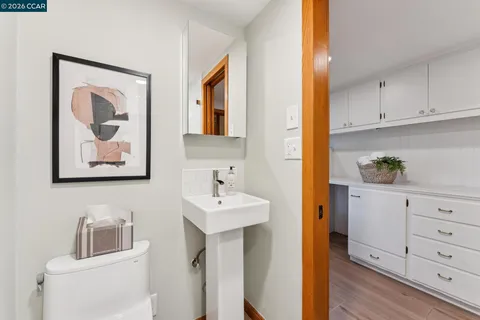 a white kitchen with sink and wooden floor
