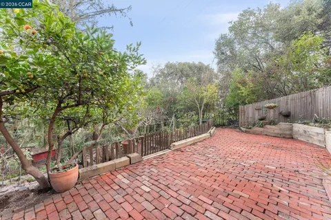 a backyard of a house with table and chairs and wooden fence