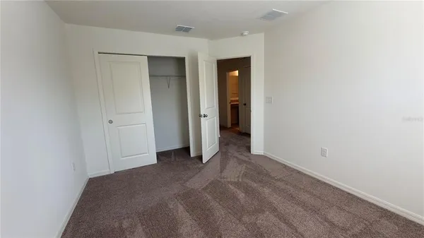 a view of an empty room with closet and a bathroom