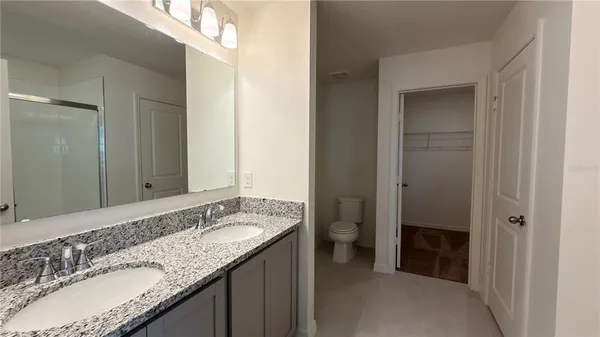 a bathroom with a granite countertop sink a toilet and a mirror