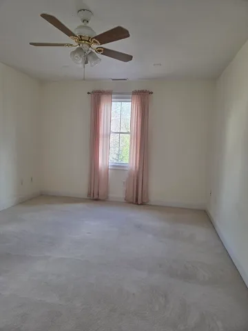 an empty room with windows and ceiling fan