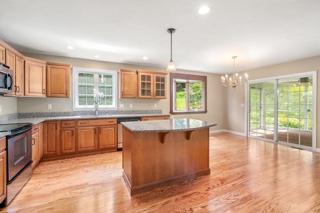 8 Reed Lane, Unit 8 Littleton, MA 01460 - Photo 10 of 37 a large kitchen with granite countertop a stove a sink a refrigerator dining table and chairs with wooden floor