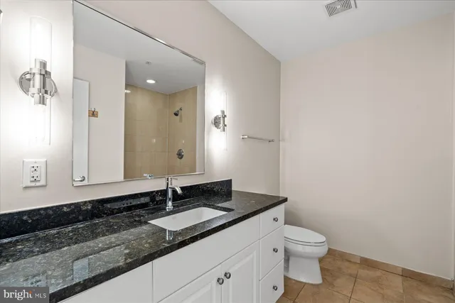 a bathroom with a granite countertop sink a toilet and a mirror