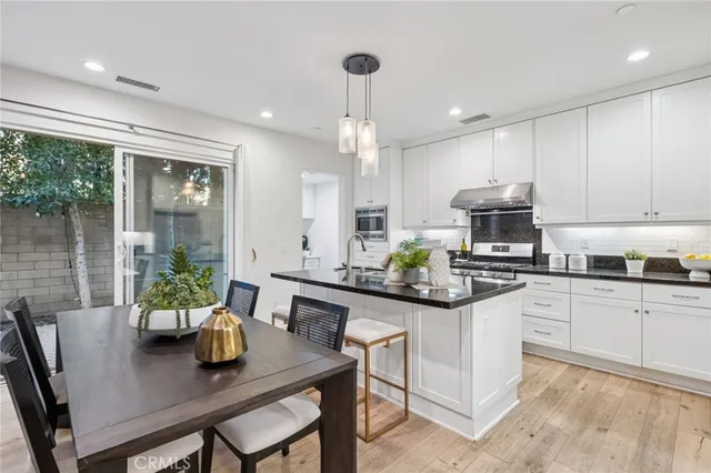 a kitchen with stainless steel appliances a dining table chairs stove and white cabinets