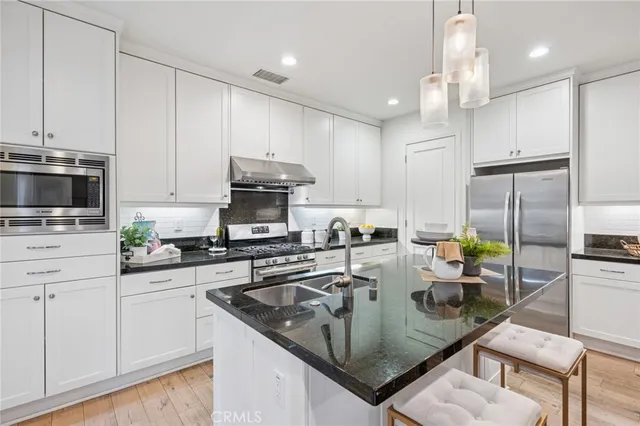 a kitchen with stainless steel appliances granite countertop a sink a stove and cabinets