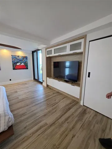 a view of an empty room with wooden floor and a fireplace