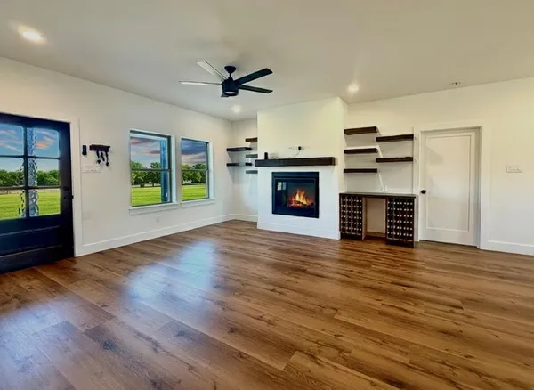 an empty room with wooden floor a fireplace and a window