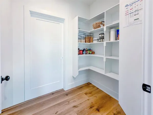 a view of an empty room with wooden floor and a fireplace