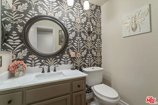 a bathroom with a toilet sink vanity mirror and vanity