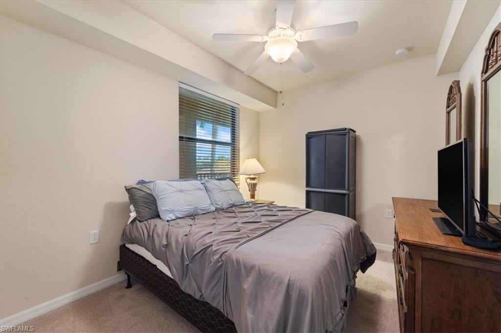 9830 Giaveno Circle, Unit 1622 Naples, FL 34113 - Photo 12 of 43 a bedroom with a large bed tv and a chandelier