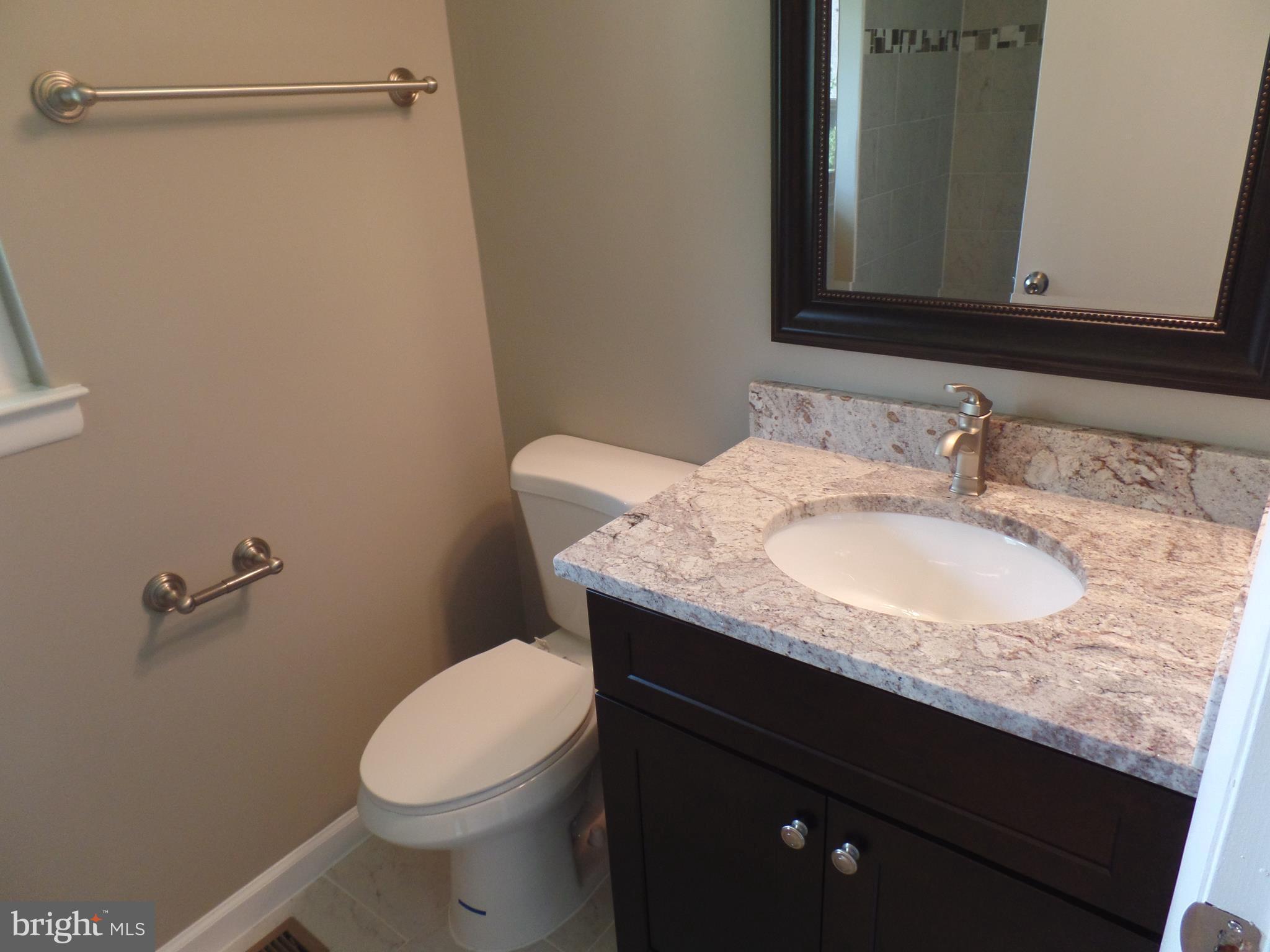 18940 Glendower Road Gaithersburg, MD 20879 - Photo 25 of 30 a bathroom with a granite countertop sink a toilet and a mirror
