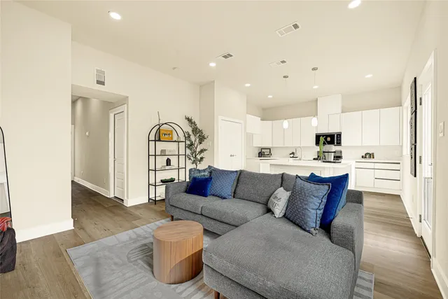 a living room with furniture and kitchen view with wooden floor