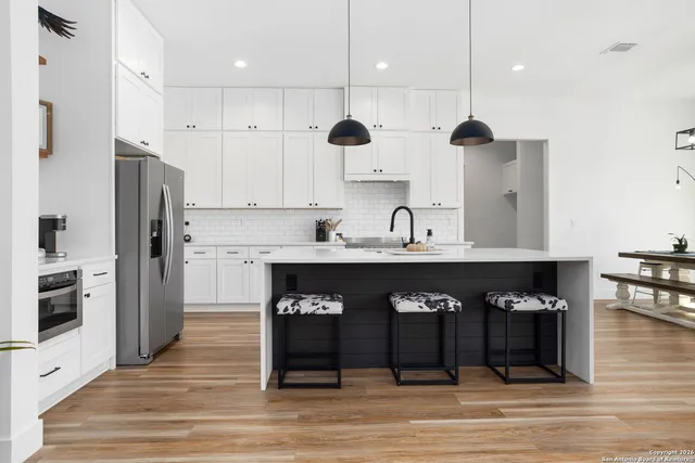 a kitchen with stainless steel appliances granite countertop a refrigerator a stove a sink and a dining table with wooden floor