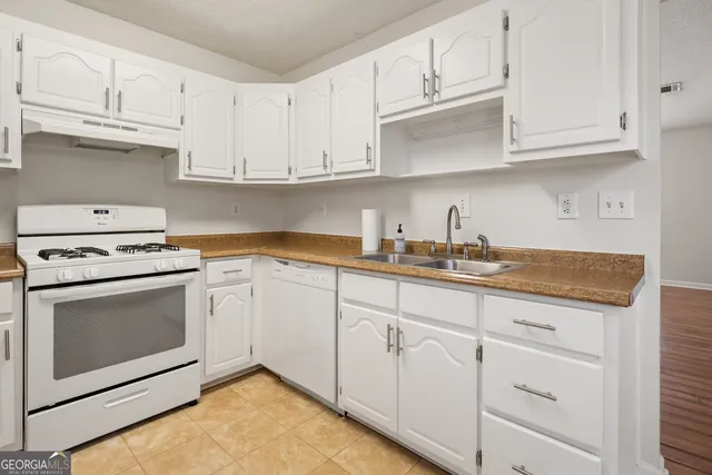 a kitchen with granite countertop white cabinets and white appliances