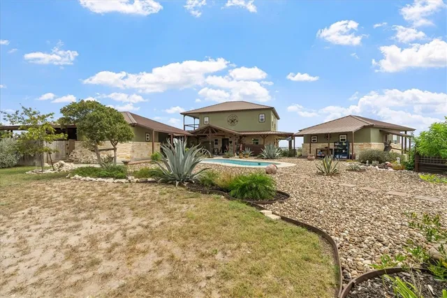 a backyard of a house with table and chairs under an umbrella