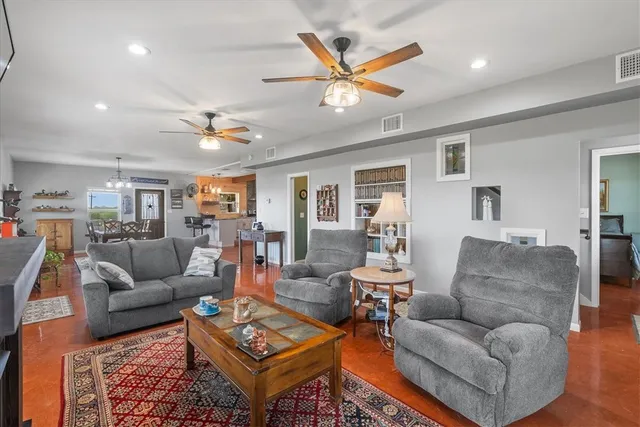 a living room with furniture kitchen view and a wooden floor