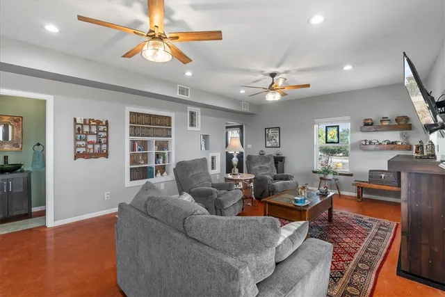 a living room with furniture a chandelier fan and a window