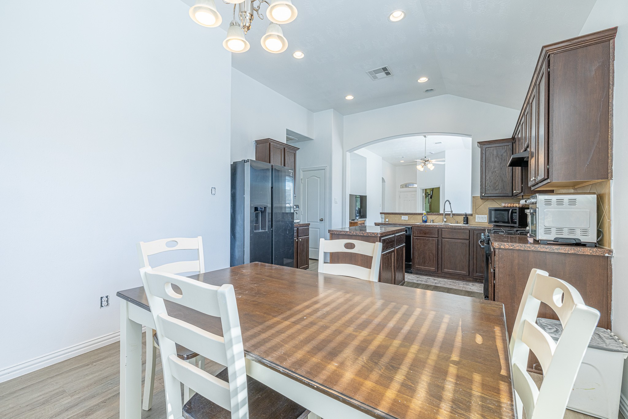 3818 Hunters Trail Baytown, TX 77521 - Photo 14 of 32 a kitchen with stainless steel appliances kitchen island granite countertop a refrigerator a stove a sink dishwasher with a dining table and chairs with wooden floor