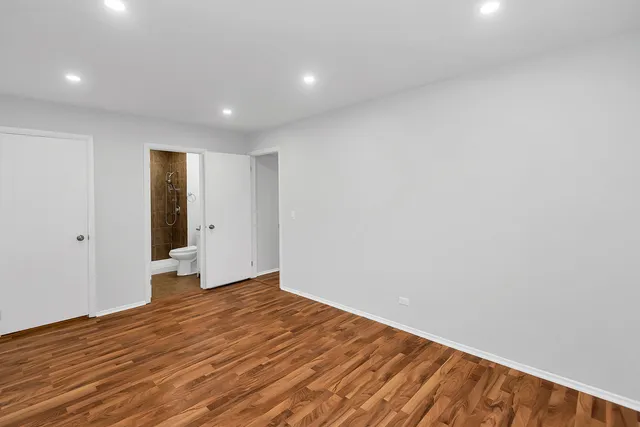 a view of an empty room with wooden floor and closet