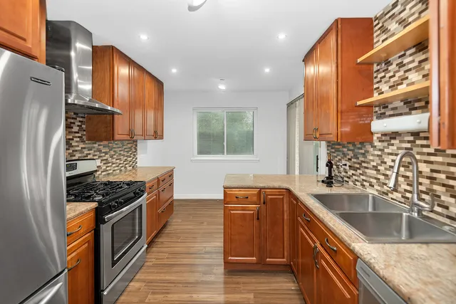 a kitchen with granite countertop a sink a counter space stainless steel appliances and cabinets