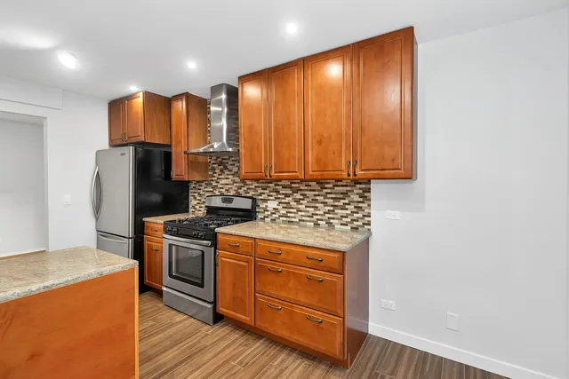 a kitchen with stainless steel appliances granite countertop a stove a refrigerator and a sink