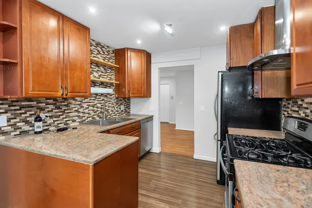 a kitchen with stainless steel appliances granite countertop a sink and a refrigerator