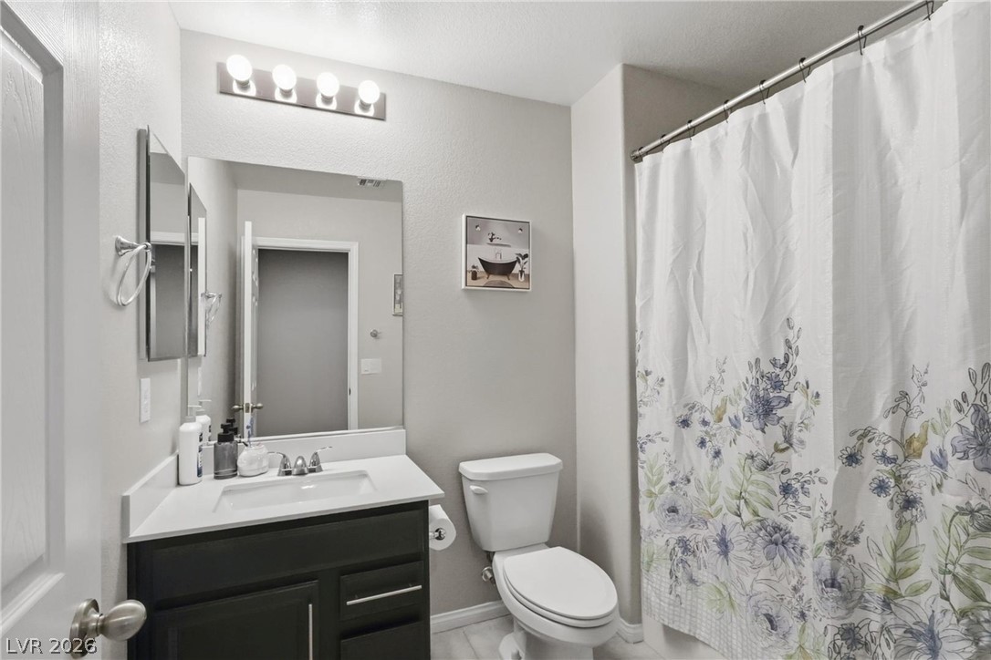 1921 Miller Ridge Avenue North Las Vegas, NV 89031 - Photo 14 of 26 This bathroom features a sleek vanity, a modern toilet, and a bright shower space.