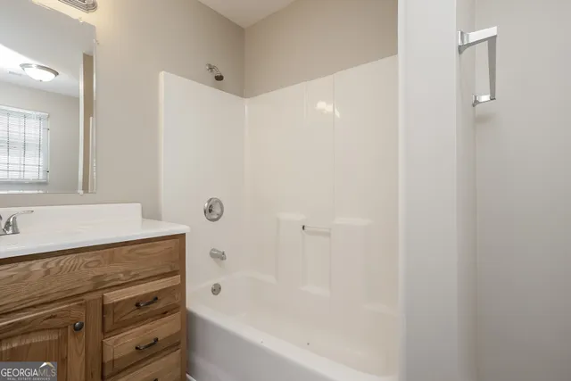 a bathroom with a granite countertop sink a mirror and a bathtub