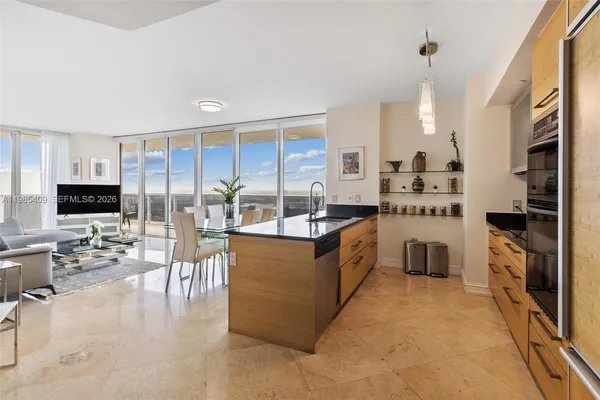 a large white kitchen with a large window and stainless steel appliances