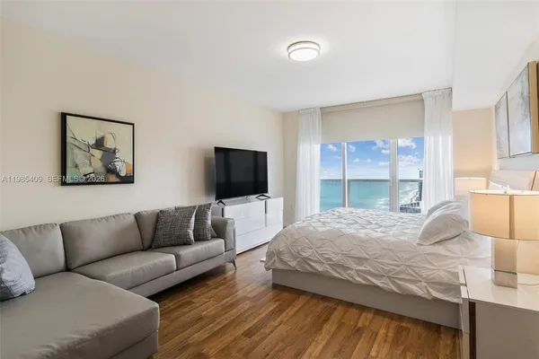 a bedroom with a bed a couch and large window