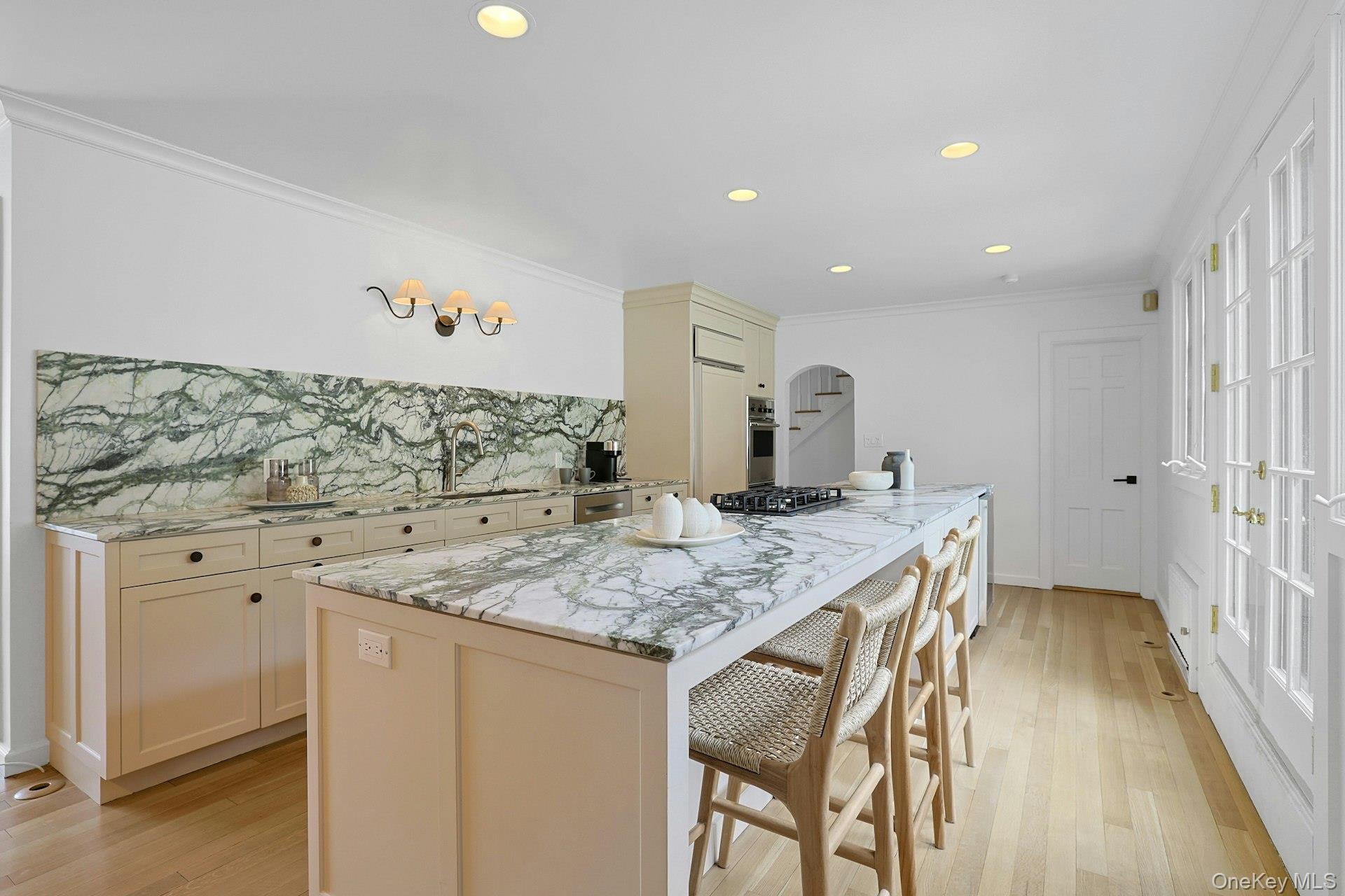 21 Tisdale Road Scarsdale, NY 10583 - Photo 12 of 40 Sleek, updated kitchen with generous center island, marble countertops and backsplash (2024), top-tier appliances (including new cooktop in 2024), new sink (2024), custom built-in cabinetry and recently sanded floors (2024). French door to fully-fenced backyad and large patio.