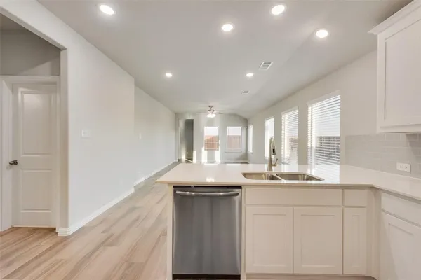 a large white kitchen with kitchen island a sink wooden floor and a refrigerator