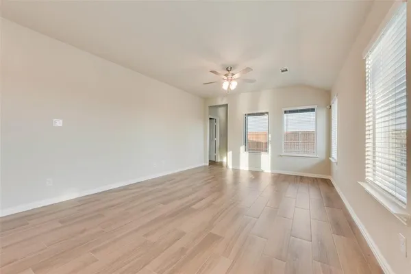 a view of an empty room with a window and a kitchen