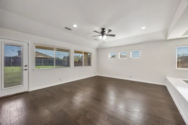 a view of an empty room with a window and wooden floor