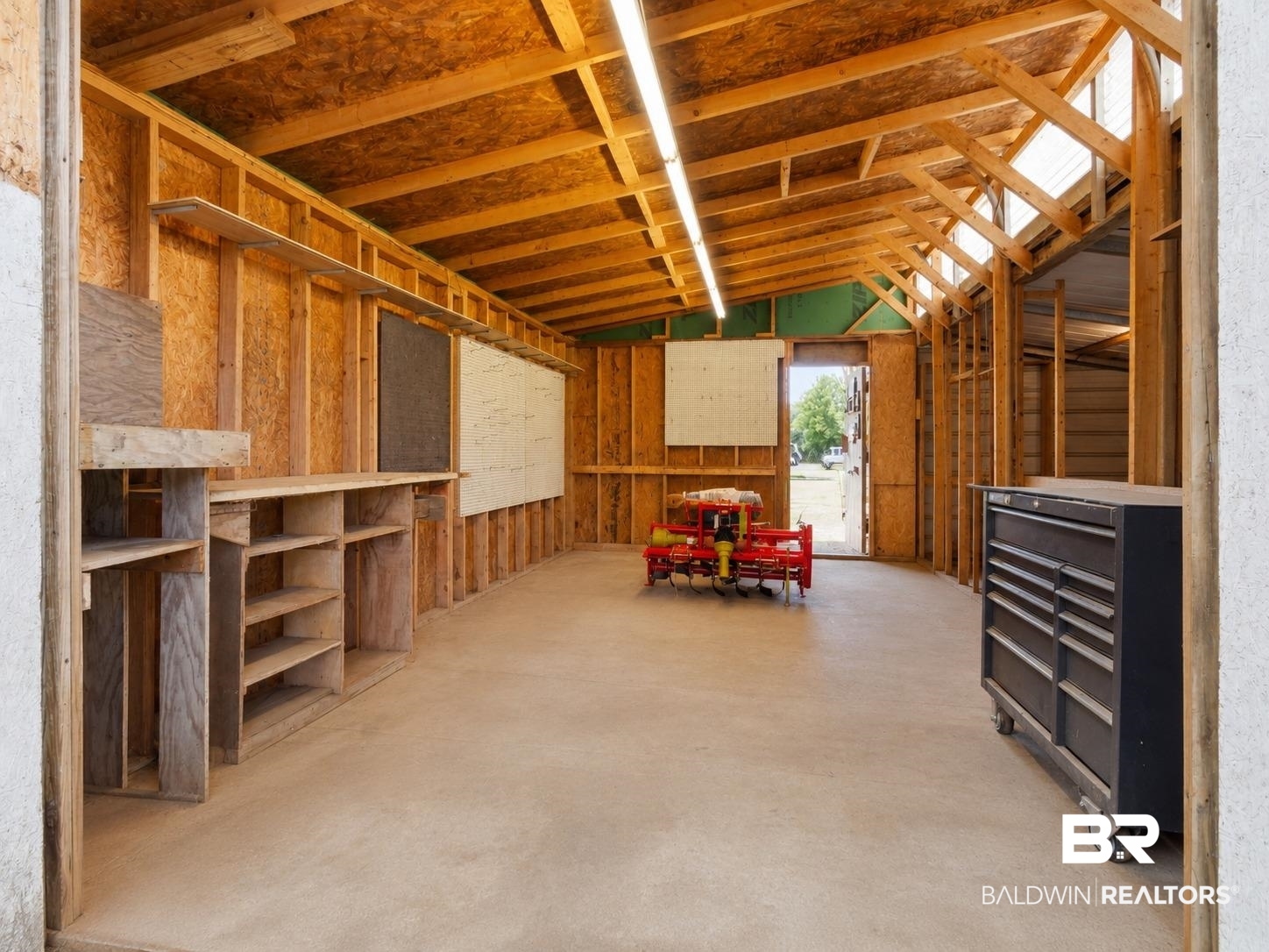 26788 Feely Road Elberta, AL 36530 - Photo 28 of 31 Spacious utility building featuring exposed wood framing, multiple built-in shelving units, concrete flooring, and skylights for natural illumination