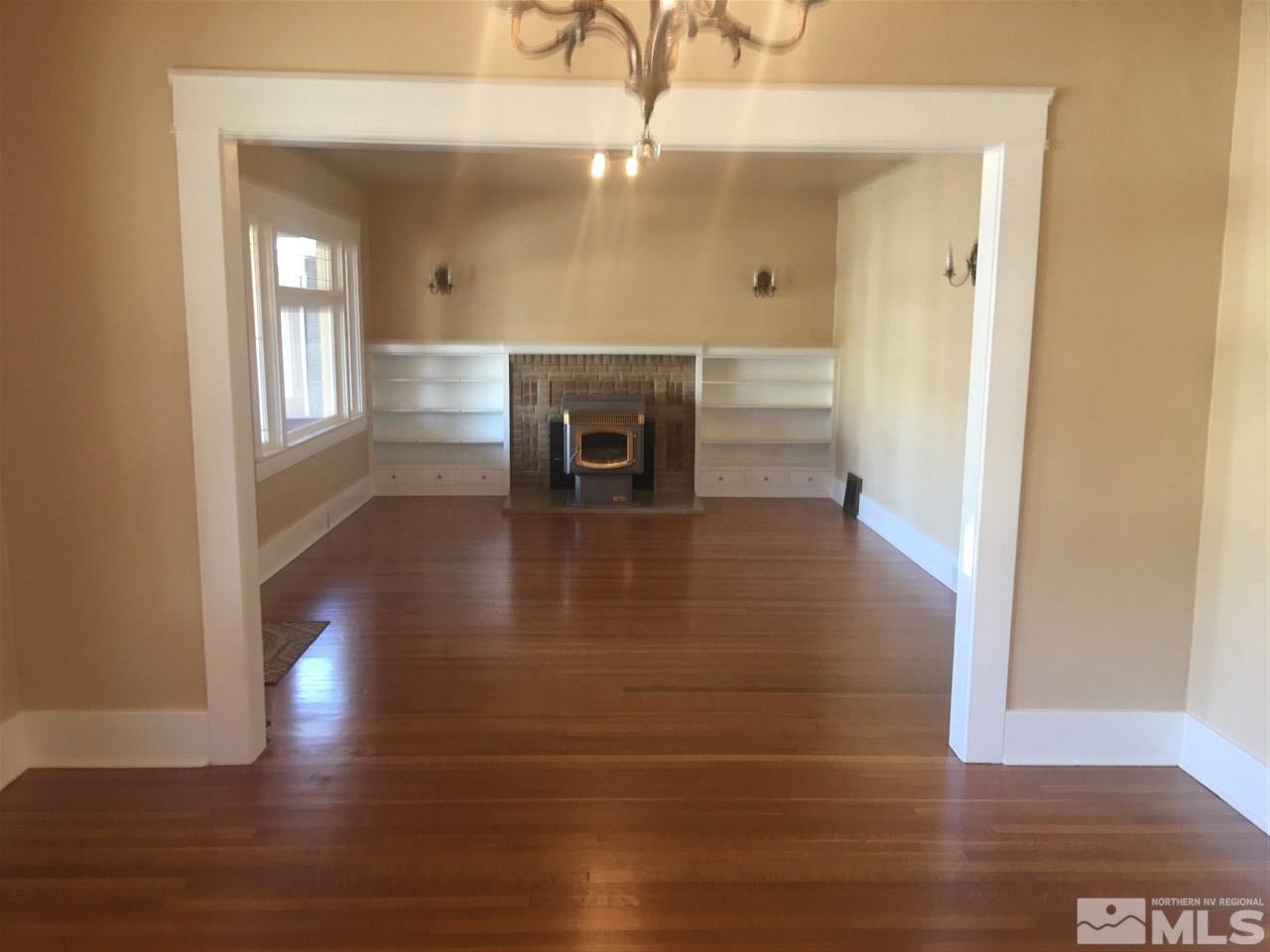 a view of a livingroom with wooden floor and a fireplace