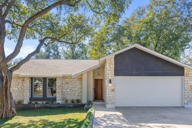 a view of a house with a yard fire pit and a large tree
