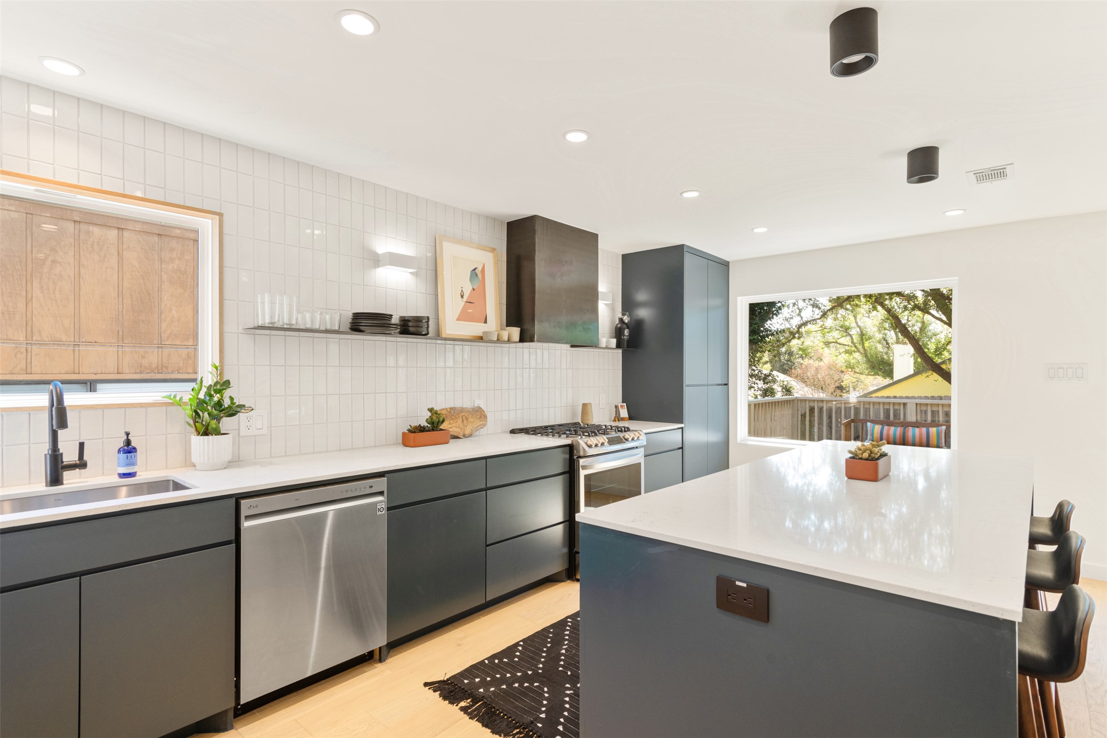 2815 Goldbridge Drive Austin, TX 78745 - Photo 24 of 40 Kitchen featuring gray cabinetry, a kitchen bar, appliances with stainless steel finishes, tasteful backsplash, and a center island